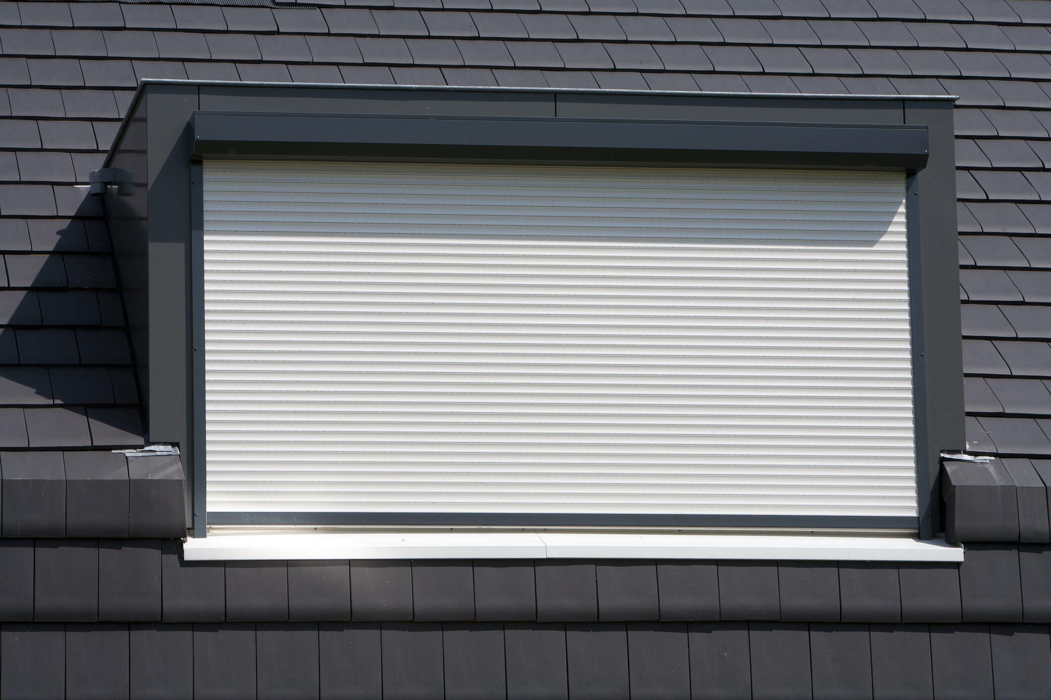 Porthole with a white rolling shutter on a black roof